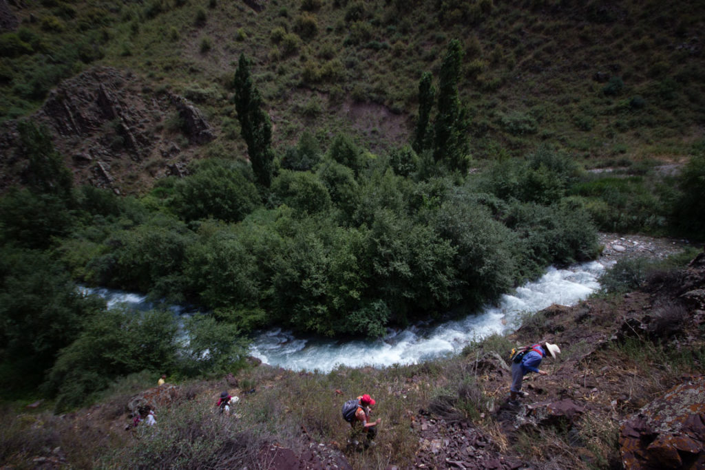 Hikers climbing a hillside above the Chong Kaindy River